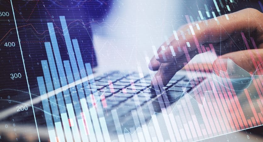 Pessoa digitando em notbook com filtro hologramas de gráficos ao representar a Economia brasileira